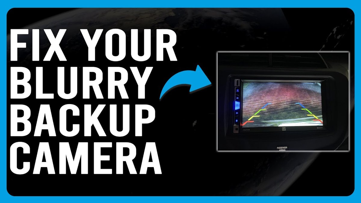 Close-up of a hand cleaning a rear backup camera lens on a vehicle at night