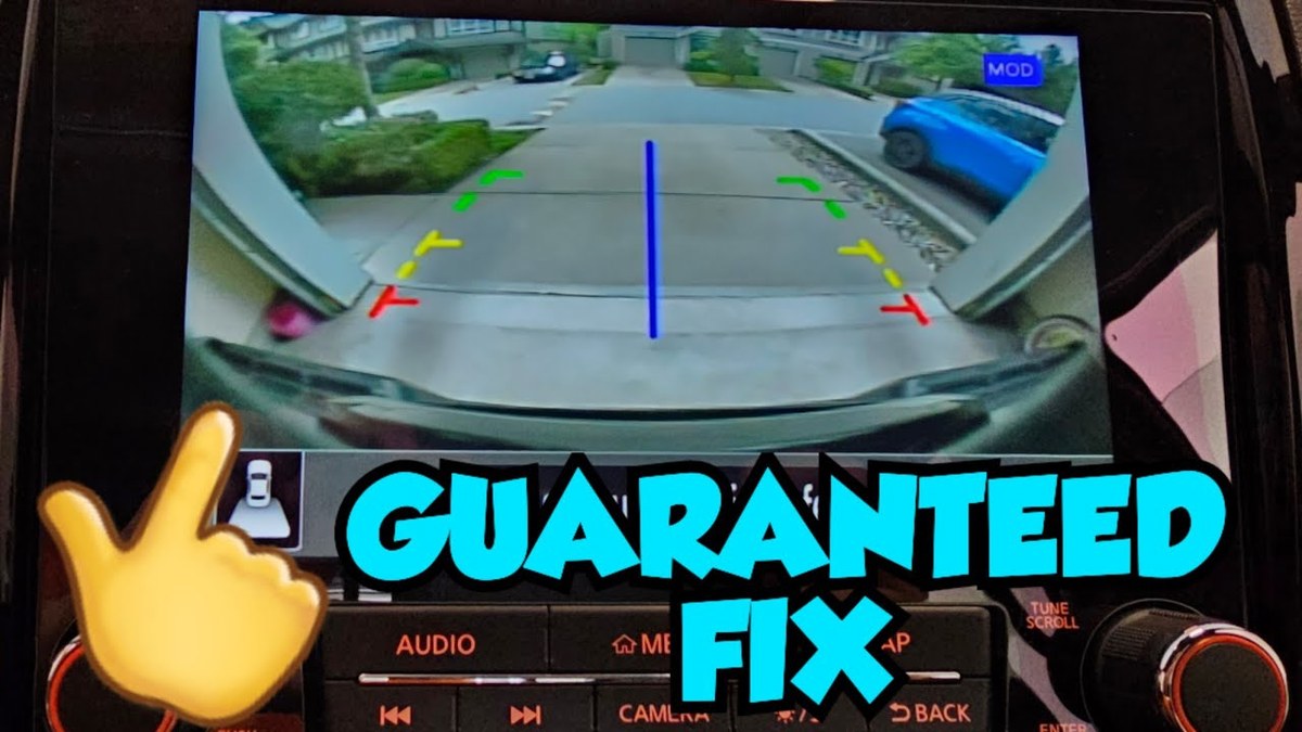 Hand pointing at cracked seal around backup camera housing