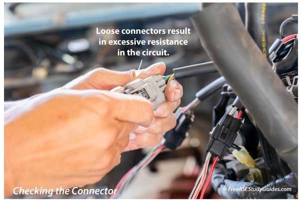 Technician inspecting backup camera wiring and connectors near the rear bumper.